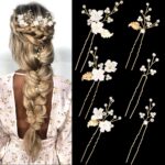 Close-up of 6 ornate gold leaf and flower pearl bridal hair pins, scattered on a soft white background.