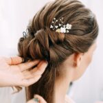 Close-up of 6 ornate gold leaf and flower pearl bridal hair pins, scattered on a soft white background.