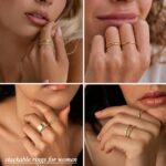 Close-up of four dainty 14K gold plated stacking rings with clear created diamonds, styled on a woman's fingers.