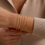 Close-up of MBW Dainty Gold Layering Bracelet Set, showing a mix of thin chains and small beads on a wrist.