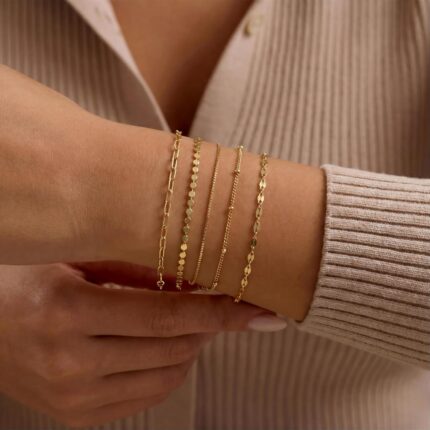 Close-up of MBW Dainty Gold Layering Bracelet Set, showing a mix of thin chains and small beads on a wrist.