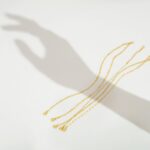 Close-up of MBW Dainty Gold Layering Bracelet Set, showing a mix of thin chains and small beads on a wrist.