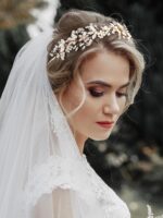 Close-up of a gold SWEETV bridal headband featuring delicate flower and leaf designs with pearls and rhinestones.