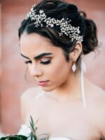 Close-up of a silver bridal headpiece featuring delicate metal leaves, luminous pearls, and sparkling clear rhinestones.