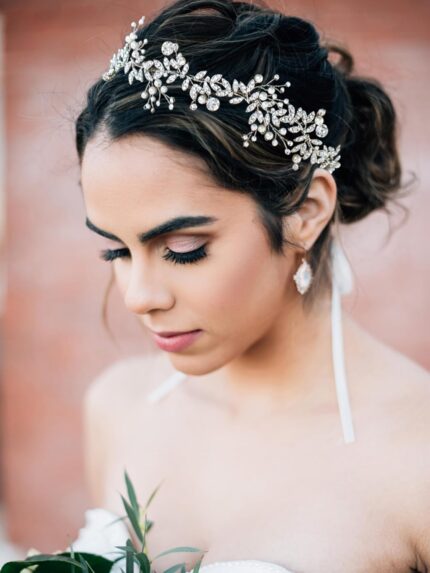 Close-up of a silver bridal headpiece featuring delicate metal leaves, luminous pearls, and sparkling clear rhinestones.