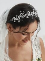 Close-up of a silver bridal headpiece featuring delicate metal leaves, luminous pearls, and sparkling clear rhinestones.