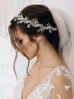 Close-up of a silver bridal headpiece featuring delicate metal leaves, luminous pearls, and sparkling clear rhinestones.