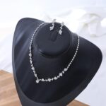 Close-up of a silver-plated necklace and matching earrings adorned with clear round rhinestones, presented in a gift box.