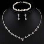 Close-up of a silver-plated necklace and matching earrings adorned with clear round rhinestones, presented in a gift box.