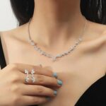 Close-up of a silver-plated necklace and matching earrings adorned with clear round rhinestones, presented in a gift box.